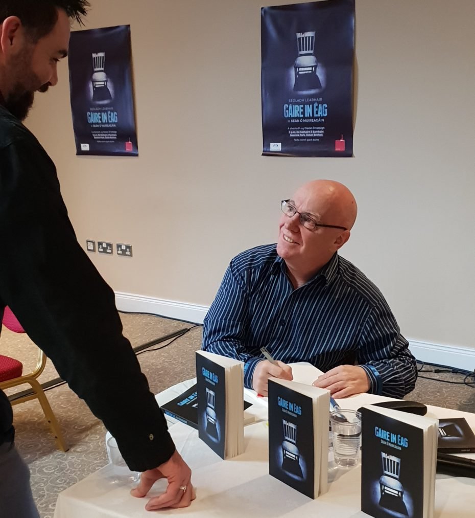 Writer Seán Ó Muireagáin signing his book at the launch of his collection of short stories Gáire in Éag
